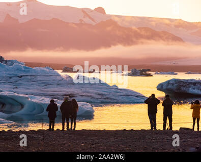 Eis Lagune. Silhouette von Touristen unter Foto, Sonnenuntergang Eis Lagune. South Island, Jokulsarlon Eis Wasserfall. Große touristische Attraktion. Stockfoto