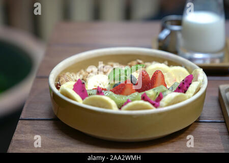 Gesunde Schüssel Müsli mit Beeren, Kiwi, Bananen, Obst. Auf einer hölzernen Tisch. Frühstück oder nahrhafte Mahlzeit Konzept. Stockfoto