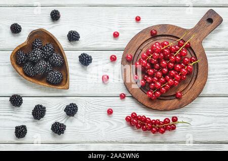 Rote und schwarze Früchte in der Küche. Rote Johannisbeere und Blackberry auf eine weiße Holztisch. Stockfoto