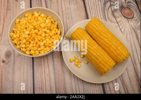 Zwei Ohren von gekochten Mais in eine Platte und ein Korn von Korn auf dem Tisch. Gesunde Ernährung. Fitness Ernährung. Für einen süßen Leckereien Stockfoto