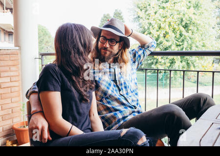 Junge schöne glückliche Paar zu Hause sitzen Terrasse umarmen - Liebe, Zärtlichkeit, Romantik Konzept Stockfoto