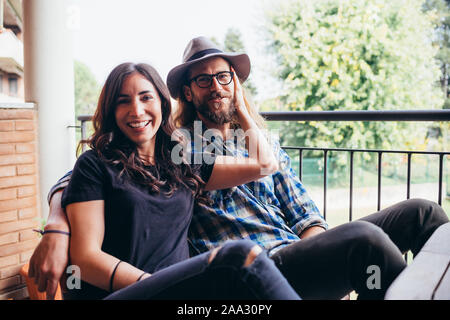 Junge schöne glückliche Paar zu Hause sitzen Terrasse umarmen - Liebe, Zärtlichkeit, Romantik Konzept Stockfoto