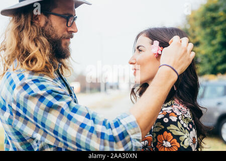 Junger Mann mit Blumen im Haar von seiner Freundin in die Augen zu schauen - Heitere, Harmonie, Intimität Konzept Stockfoto