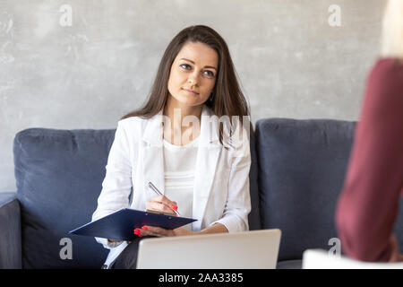 Ernsthafte buisnesswoman hält Tablet in der Hand und macht Notizen auf Papier. Stockfoto