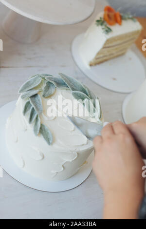 Frau schneiden einen Karottenkuchen mit Blättern dekoriert Stockfoto