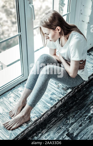 Unglücklich blassen Frau sitzt auf dem Fensterbrett Stockfoto