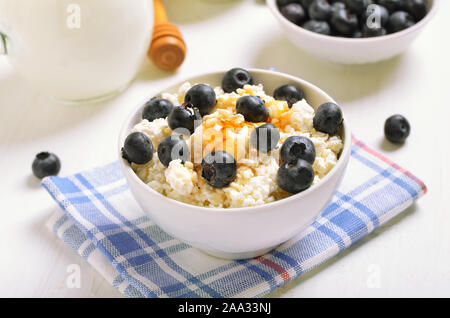 Hüttenkäse und Blaubeeren mit Honig in weiße Schüssel Stockfoto