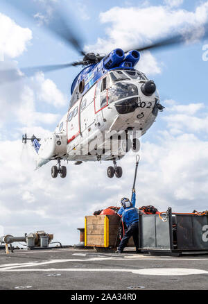 Philippinischen MEER (Nov. 15, 2019) der Bootsmann Mate 3. Klasse Dylan Virrueta-Torres, von Chico, Calif., Front, unterstützt die Bootsmann Mate 3. Klasse Avery Gonzalez, von Houston, wie bereitet er eine Ladung schließen Sie ein SA-330 Puma Helikopter auf dem Flugdeck der Arleigh-Burke-Klasse geführte Anti-raketen-Zerstörer USS Milius (DDG69) als das Schiff eine Auffüll-anforderung führt-auf-See mit der Lewis und Clark-Klasse Dry Cargo ship USNS Washington Kammern (T-AKE 11) Während der jährlichen Übung (ANNUALEX) 19. Milius beteiligt sich an ANNUALEX 19, eine bilaterale Übung, die weitere Koordination entwickelt und Interop Stockfoto