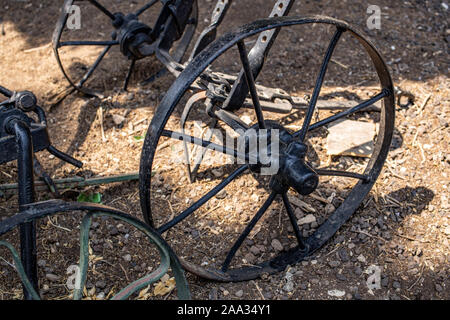 Fragment der Räder ein altes Eisen schwarz Landwirtschaftliche auf getrocknete Gras in der israelischen Stadt von Rosh Pina Pflug Stockfoto