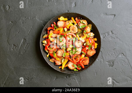 Gegrilltes Gemüse mit Würstchen und Kräuter in der Pfanne auf einem dunklen Hintergrund, Ansicht von oben Stockfoto