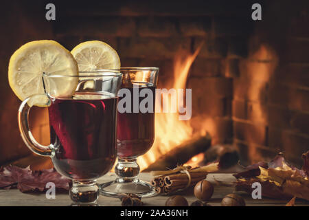 Zwei Gläsern Glühwein auf einer hölzernen Tisch vor einem brennenden Kamin. Stockfoto