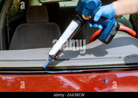 Close up Auto Glasur Arbeiter Silikon Leim einer Windschutzscheibe eines Autos an einer Tankstelle Glas für Austausch Stockfoto