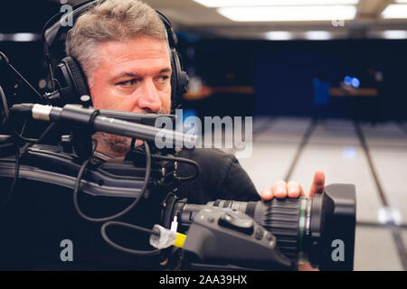 Professionelle Kameramann mit Kopfhörern mit HD-Camcorder im TV-Studio Stockfoto