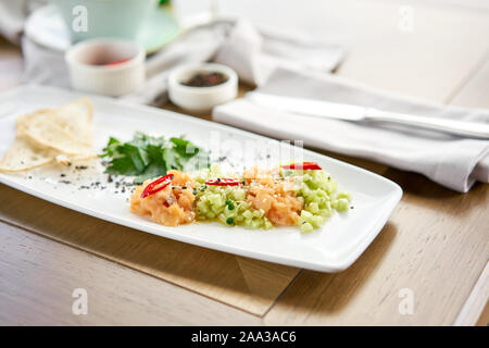 Lachstatar mit Gurke und Sesam. Verkostung Teller auf einen hölzernen Tisch. Stockfoto