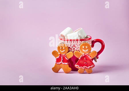 Weihnachten Lebkuchen Männer und heiße Schokolade trinken mit Marshmallow auf rosa Hintergrund Stockfoto