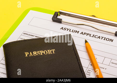 Asyl Konzept, die einen Antrag auf Asyl auf gelbem Hintergrund mit einem Stift und einem Pass Stockfoto