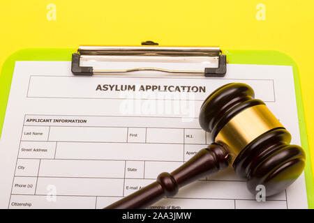 Asyl Konzept, die einen Antrag auf Asyl auf einem gelben Hintergrund mit einem Hammer Stockfoto