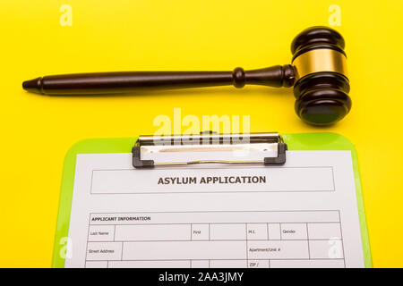 Asyl Konzept, die einen Antrag auf Asyl auf einem gelben Hintergrund mit einem Hammer Stockfoto