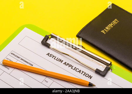Asyl Konzept, die einen Antrag auf Asyl auf gelbem Hintergrund mit einem Stift und einem Pass Stockfoto