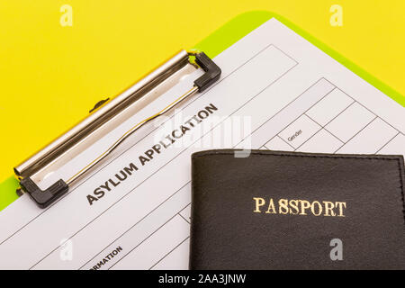 Asyl Konzept, die einen Antrag auf Asyl auf gelbem Hintergrund mit einem Pass Stockfoto