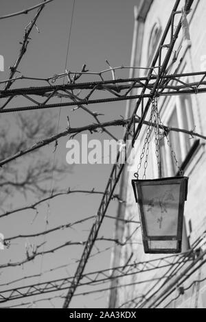 Straße dekorative Lampe an Ketten hängend auf einer metallischen Struktur. Schwarz und Weiß Foto Stockfoto