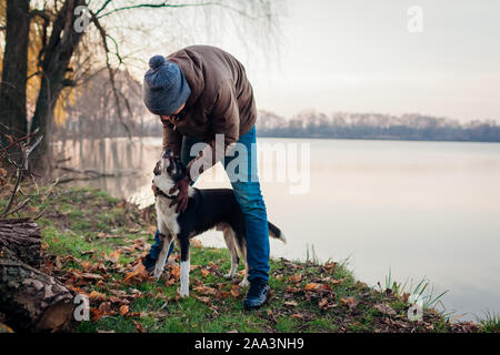 Mann spielt mit Hund im Herbst Park mit See. Happy pet Spaß zu Fuß im Freien Stockfoto