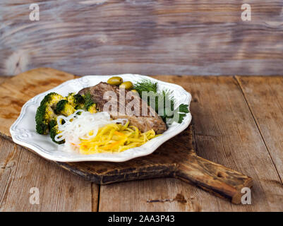 Gegrillte gekochtes Rindfleisch, Brokkoli, Gemüse spaghetti Shirataki, Rettich daikon Salat, Oliven. Paleo und keto Diät Teller. Rustikale Hintergrund anzeigen. Sele Stockfoto