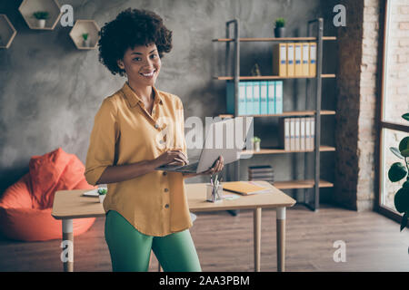 Portrait von coolen Afro American Girl Start-up-Unternehmer halten Computer Führung watch Arbeit seminar Konzept tragen gelb Shirt grüne Hosen Hosen Stockfoto