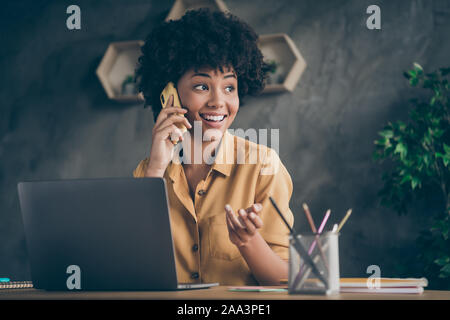 Foto fröhliche, positive Mixed-race hübsche Frau arbeiten als Content Manager der Organisation mit ihren Kunden per Telefon lächeln toothily Stockfoto