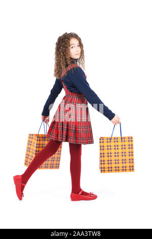 Kind mit einem gelben Verpackung karierten Textur auf weißem Hintergrund. Urlaub, Shopping. Kid Happy Shopping in der Mall. Glückliches Mädchen mit Stockfoto