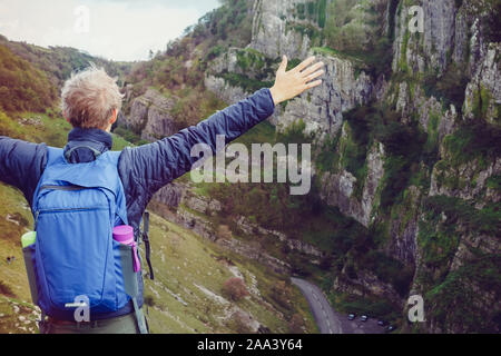 Zurück Junge Wanderer mit Rucksack stand auf dem Gipfel des Berges mit erhobenen Händen genießen Felsen auf die Landschaft. Reisen lifestyle Fernweh aufkommen Stockfoto