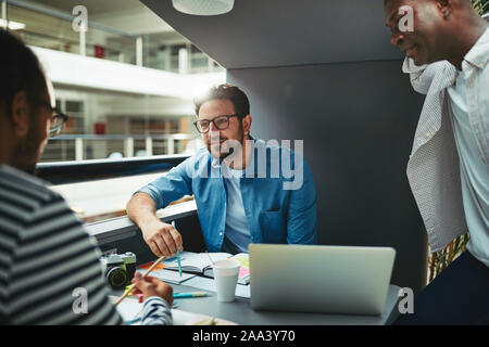 Team von kreativen Arbeiten an einem Projekt zusammen während der Sitzung in einer Sitzung pod in der Lobby eines modernen Büro Stockfoto