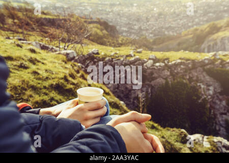 Close up Thermoskanne Kaffee oder Tee in der männlichen Händen. Zwei Freunde, die an der Spitze des Berges geniessen trinken und Blick auf landsape der Natur. Travel lif Stockfoto