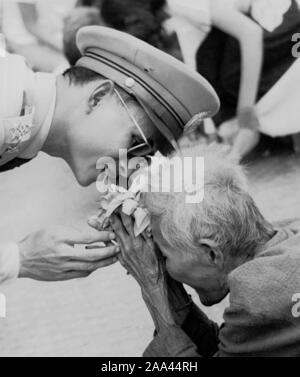 "TUM Channich" alte Frau 102 Jahre begrüßen den König Bhumibol Adulyadej am Nachmittag des 13. November 1955 Für den ersten Besuch im Nordosten. Eine alte Dame geht Willkommen bei Pink Lotus 3. Von morgens bis zum Nachmittag die Sonne brennt, bis die Lilien in der Hand hältst. Wenn der König Bhumibol Adulyadej ist da die alte Dame warf die Lilien, verdorrte drei bis über den Kopf. Der König nach unten gebogen, bis das Gesicht war fast in der Nähe der Leiter der alten Frau und lächelte sanft und nahm auch die Hand berühren die Hände der alten Frau in den eindrucksvollsten Thailänder. Stockfoto