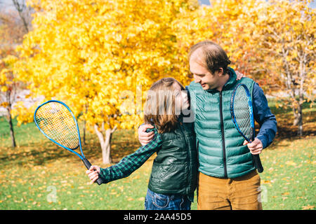 Vater und Sohn im Herbst park mit Tennisschläger Stockfoto