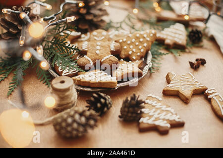 Weihnachten Lebkuchen Cookies auf vintage Platte und Anis, Zimt, Tannenzapfen, zeder Filialen mit Golden Lights auf rustikalen Tisch. Traditionelle gebacken Stockfoto