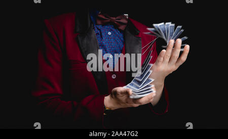 Magier zeigt Trick mit Spielkarten auf dunklem Hintergrund, Konzept stand-up. Stockfoto