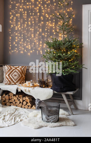 Holzbank stand in der Ecke des Zimmers. Tanne in schwarz Warenkorb stehen auf IT- und Brennholz legt. Stockfoto