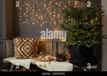 Holzbank stand in der Ecke des Zimmers. Tanne in schwarz Warenkorb stehen auf IT- und Brennholz legt. Stockfoto