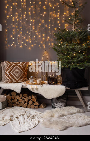 Holzbank stand in der Ecke des Zimmers. Tanne in schwarz Warenkorb stehen auf IT- und Brennholz legt. Stockfoto