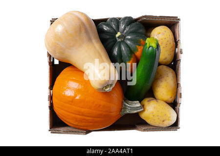 Gemüse aus der Nähe. Frische, Bio Kürbis, Acorn Squash, butternut Kürbis, Zucchini und Kartoffeln in eine Holzkiste, Nahaufnahme, Ansicht von oben, isoliert Stockfoto