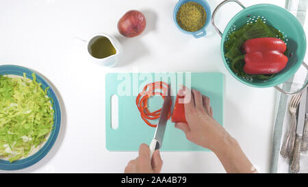 Roter Pfeffer Schichten in der Nähe auf einem Schneidebrett. Salat auf einen Teller, auf weißem Hintergrund schliessen. Frische organische Römersalat, rot Pfeffer, auf Stockfoto