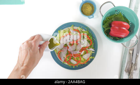 Salat auf einen Teller, auf weißem Hintergrund schliessen. Frische organische Römersalat, Paprika, Zwiebel, einige Gewürze und Olivenöl. Ansicht von oben, w Stockfoto
