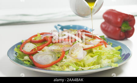 Salat auf einen Teller, auf weißem Hintergrund schliessen. Frische organische Römersalat, Paprika, Zwiebel, einige Gewürze und Olivenöl. Stockfoto