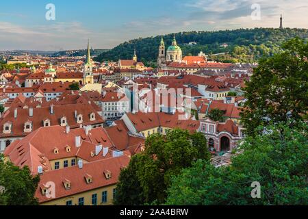 Prag, Tschechische Republik - 20. Juli 2019: Blick auf die roten Dächer, Stadtbild mit den Kirchen und den fernen Petrin Hügel mit einem Turm. Blauer Himmel mit Wolken. Stockfoto