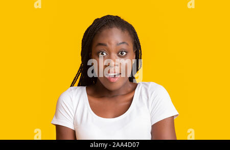 Portrait von schockiert afrikanisches Mädchen auf gelbem Hintergrund Stockfoto