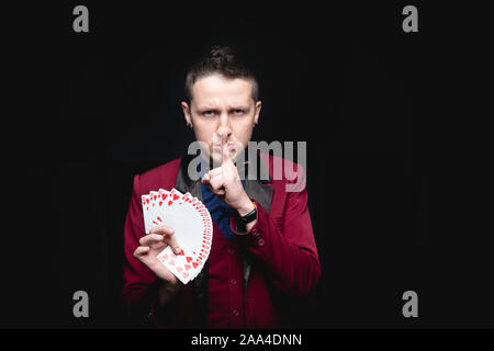 Magier zeigt Trick mit dem Spielen des gleichen Karten auf dunklem Hintergrund. Offenlegung von konzentrieren. Stockfoto
