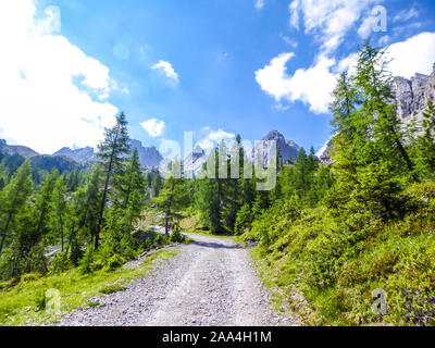 Eine kleine und geschotterten Straße in der Bergwelt der Lienzer Dolomiten, Österreich. Die Berge sind teilweise mit grünen Büschen überwachsen. Gefährliche Berg Stockfoto