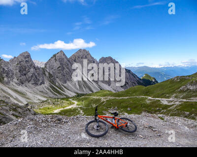 Mountainbike auf der Seite einer Geschotterten Straße in hohen Bergkette der Lienzer Dolomiten, Österreich liegen. Die Pisten sind unfruchtbar mit wenig Gras auf Sie. Stockfoto