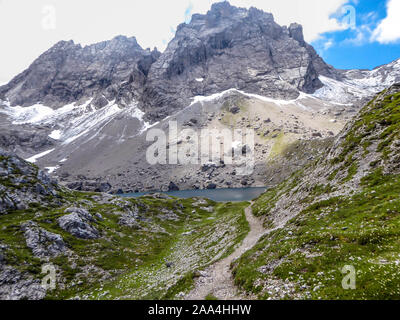 Tal mit einem kleinen See in der Mitte, zwischen scharfen und steinige Gebirge der Lienzer Dolomiten, Österreich. Die Pisten sind unfruchtbar, mit wenig Stockfoto